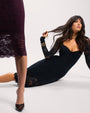 Model laying in Seamed Lushy Long Sleeve Midi Dress - Lace Black behind model in Seamed Lushy Long Sleeve Midi Dress - Lace Garnet