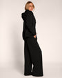 Full body side view of model wearing Fleecey Wide Leg Pull On Pant - Black paired with the Swuity Convertible Jacket - Black